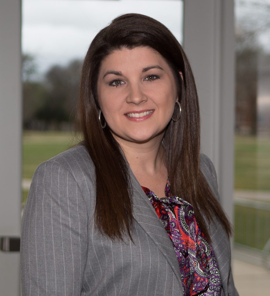 female with long brown hair and brown eyes wearing a gray stiped business suit. 